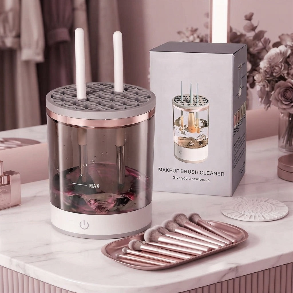 Automatic makeup brush cleaner device with organized makeup brushes on a modern vanity table in a blush-toned room.
